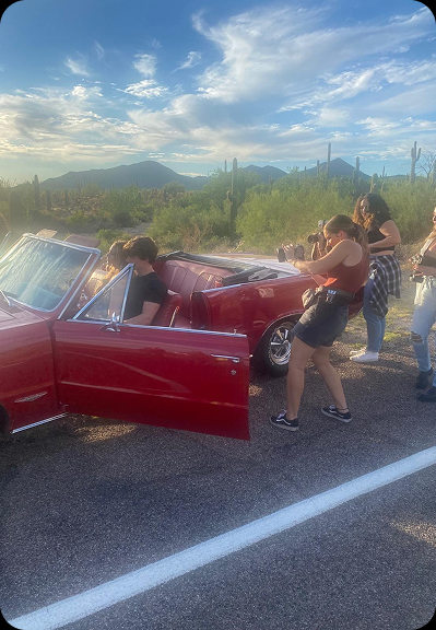 Multiple photographers capturing a red convertible